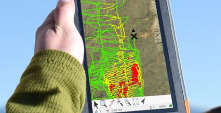 Hand holding a GPS device displaying a colorful map.