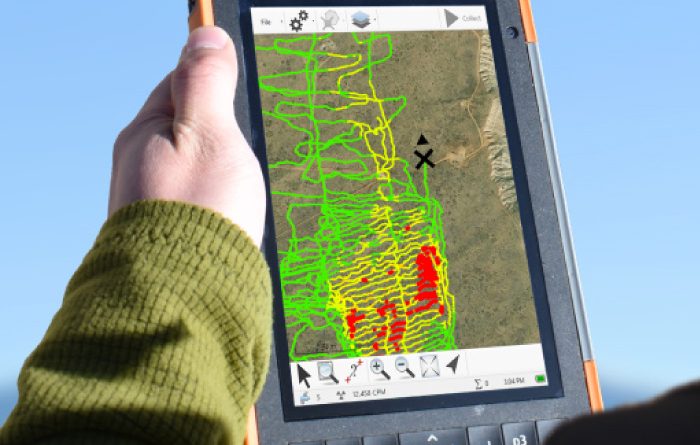 Hand holding a GPS device displaying a colorful map.