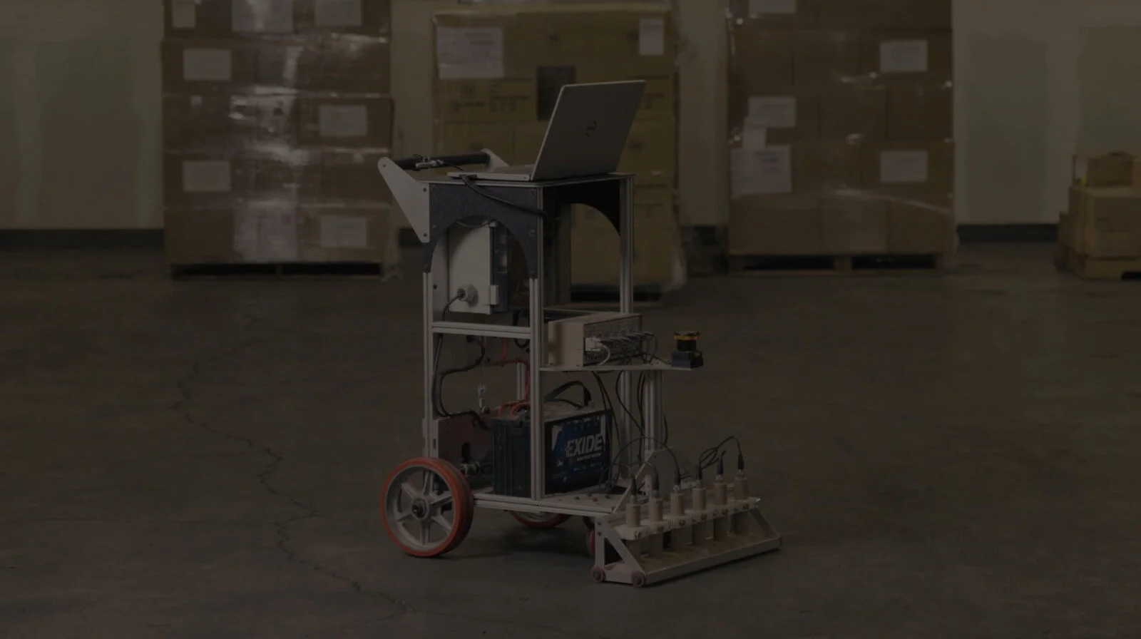 A custom-built robot with wheels and mechanical arms in a warehouse.